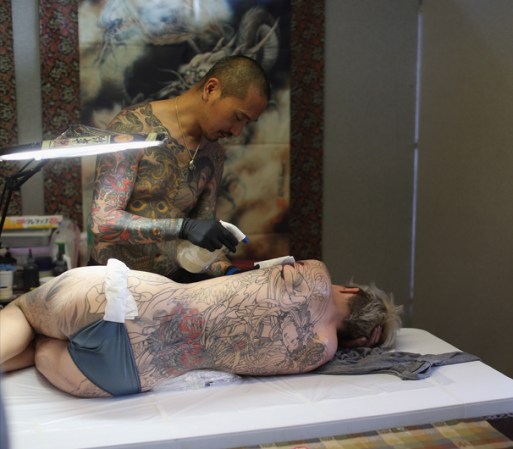 Una entusiasta del tatuaje yace sobre un costado mostrando su espalda tatuada.