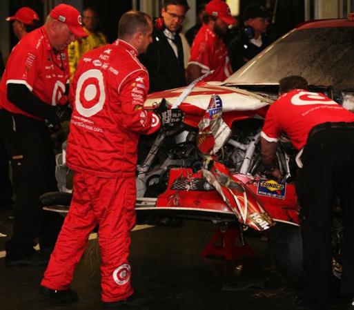 Montoya frente a su carro magullado mientras es reparado.