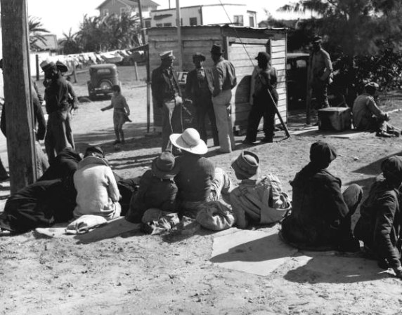Trabajadores esperando el camión que los llevará a los campos de frijol - Lago Harbor, Florida, 1939.