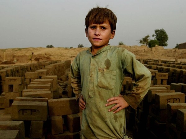 OCTUBRE, 2001: Los niños que trabajan son comunes en el tercer mundo, como éste en Paquistán, colocando ladrillos.