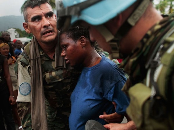 ENERO, 2011: Soldados uruguayos de la ONU ayudan a una haitiana a conseguir comida.