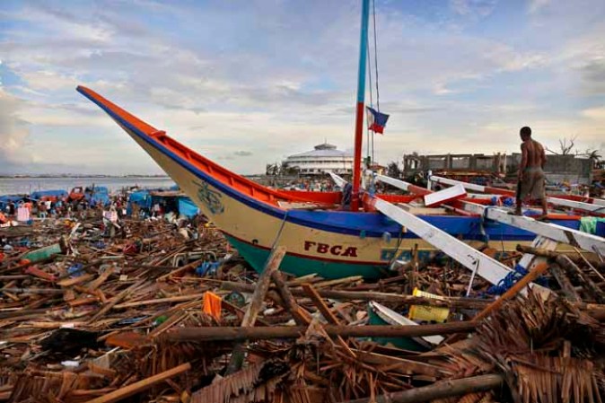 TACLOBAN, PHILIPPINES - NOVEMBER 13: A resident walks amongst the devastation in the aftermath of Typhoon Haiyan on November 13, 2013 in Tacloban, Leyte, Philippines. Typhoon Haiyan, packing maximum sustained winds of 195 mph (315 kph), slammed into the southern Philippines and left a trail of destruction in multiple provinces, forcing hundreds of thousands to evacuate and making travel by air and land to hard-hit provinces difficult. Around 10,000 people are feared dead in the strongest typhoon to hit the Philippines this year. (Photo by Kevin Frayer/Getty Images)