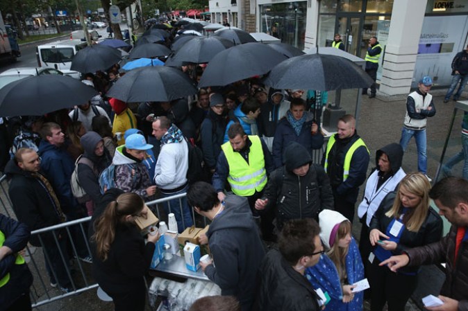 BERLIN, GERMANY - SEPTEMBER 20: People line up outside the Berlin Apple Store to buy the new Apple iPhone 5S and 5C smartphones on the first day of sales on September 20, 2013 in Berlin, Germany. The new iPhone 5S and 5C phones went on sale all over the world today and hundreds of customers waited outside the Berlin store in the rain to be among the first to buy the new phones starting at 8am. (Photo by Sean Gallup/Getty Images)