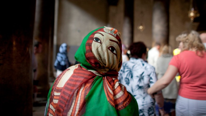 Una mujer con la cabeza cubierta por un pañuelo camina por la Iglesia de la Natividad.