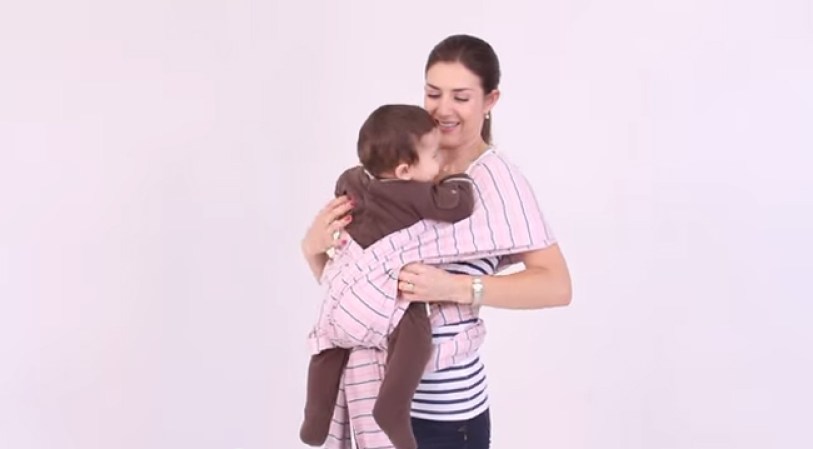 Pon al bebe dentro del rebozo haciendo que sus piernas cuelguen a sus lados.