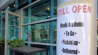 Sign on facade at a restaurant announcing that the restaurant would remain open for takeout orders during an outbreak of the COVID-19 coronavirus.