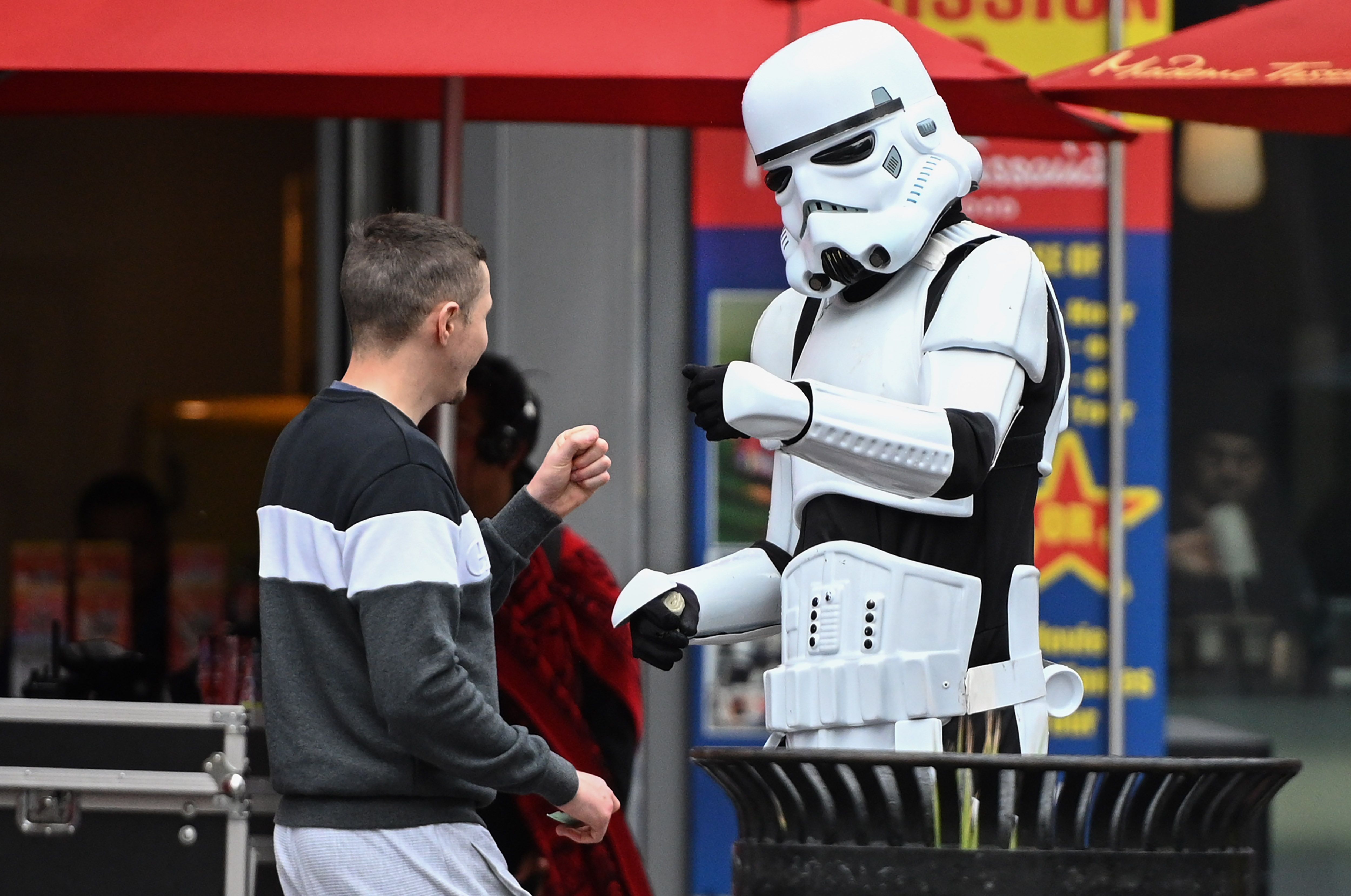 Una persona en un disfraz de Stormtrooper que posa para instantáneas con turistas a cambio de golpes de puño como propina con un transeúnte, en el Bulevar Hollywood, en Hollywood, California, 10 de marzo de 2020. (Foto por Robyn Beck / AFP) (Foto por ROBYN BECK / AFP a través de Getty Images)