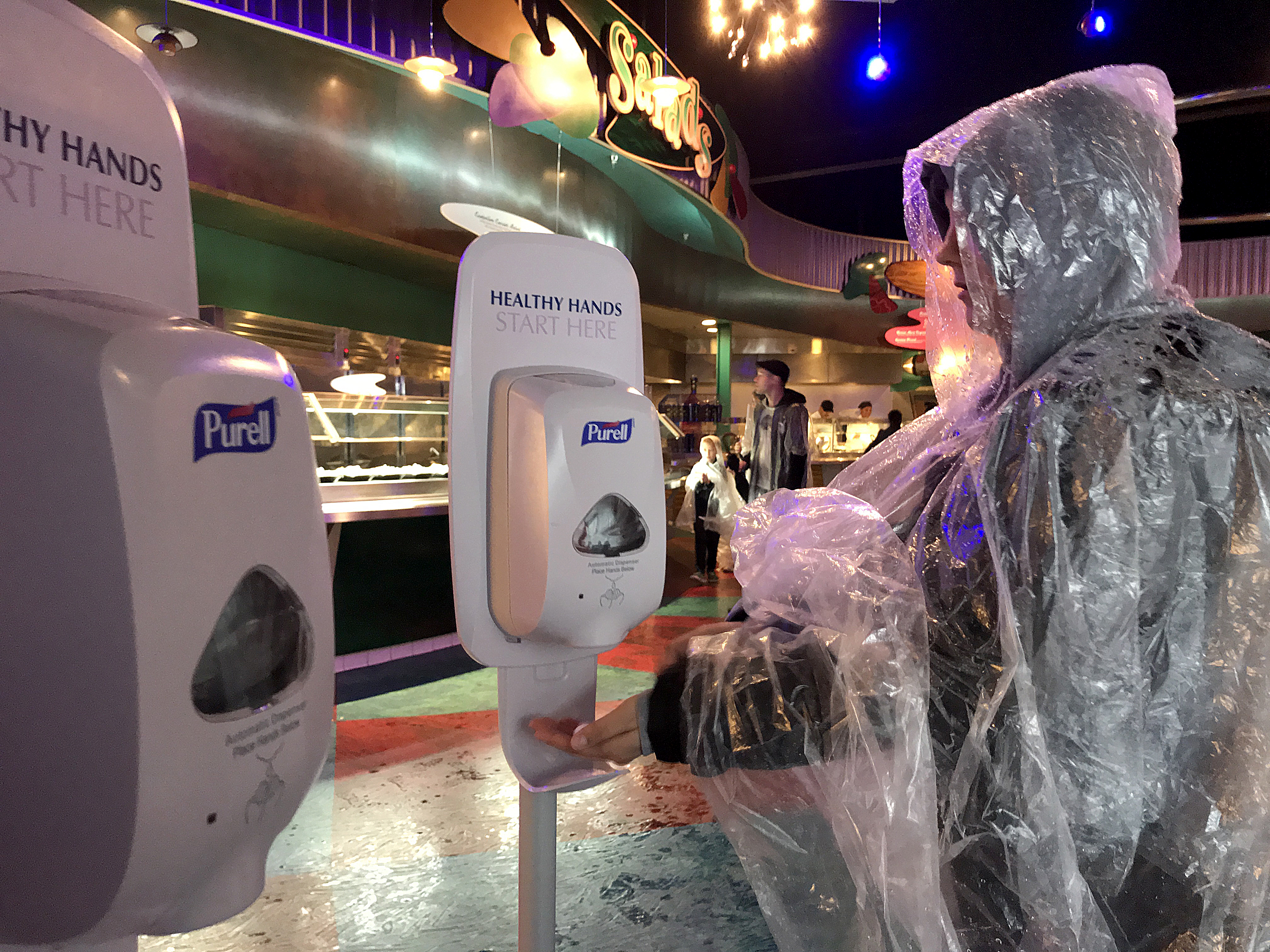 Un visitante de Disneyland usa una nueva estación de desinfección de manos dentro del Alien Pizza Planet antes de pedir comida mientras visita Disneyland en medio de lluvias en Anaheim, California, el 12 de marzo de 2020. Disneyland cerrará temporalmente el Disneyland Resort en Anaheim en respuesta a la creciente amenaza planteado por la pandemia de coronavirus. (Foto de Allen J. Schaben / Los Angeles Times a través de Getty Images)