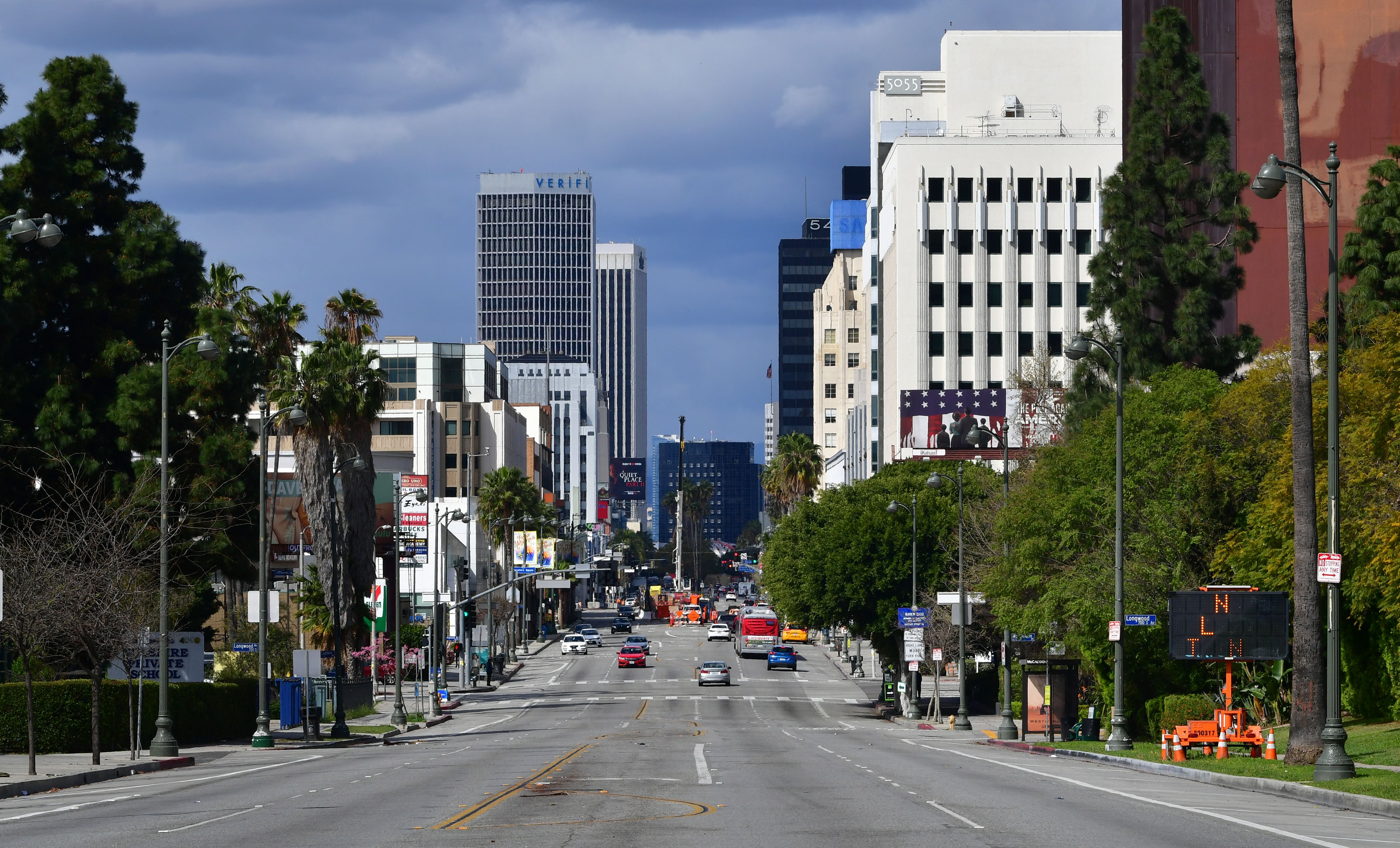 Pocos autos se ven en un viaje matutino ligero a lo largo de Wilshire Boulevard en Los Ángeles, California, el 17 de marzo de 2020, después que la epidemia de coronavirus condujo al cierre de restaurantes y escuelas  y mientras los trabajadores trabajan desde casa en un esfuerzo por alentar el distanciamiento social. (Foto de Frederic J. BROWN / AFP) (Foto de FREDERIC J. BROWN / AFP a través de Getty Images)