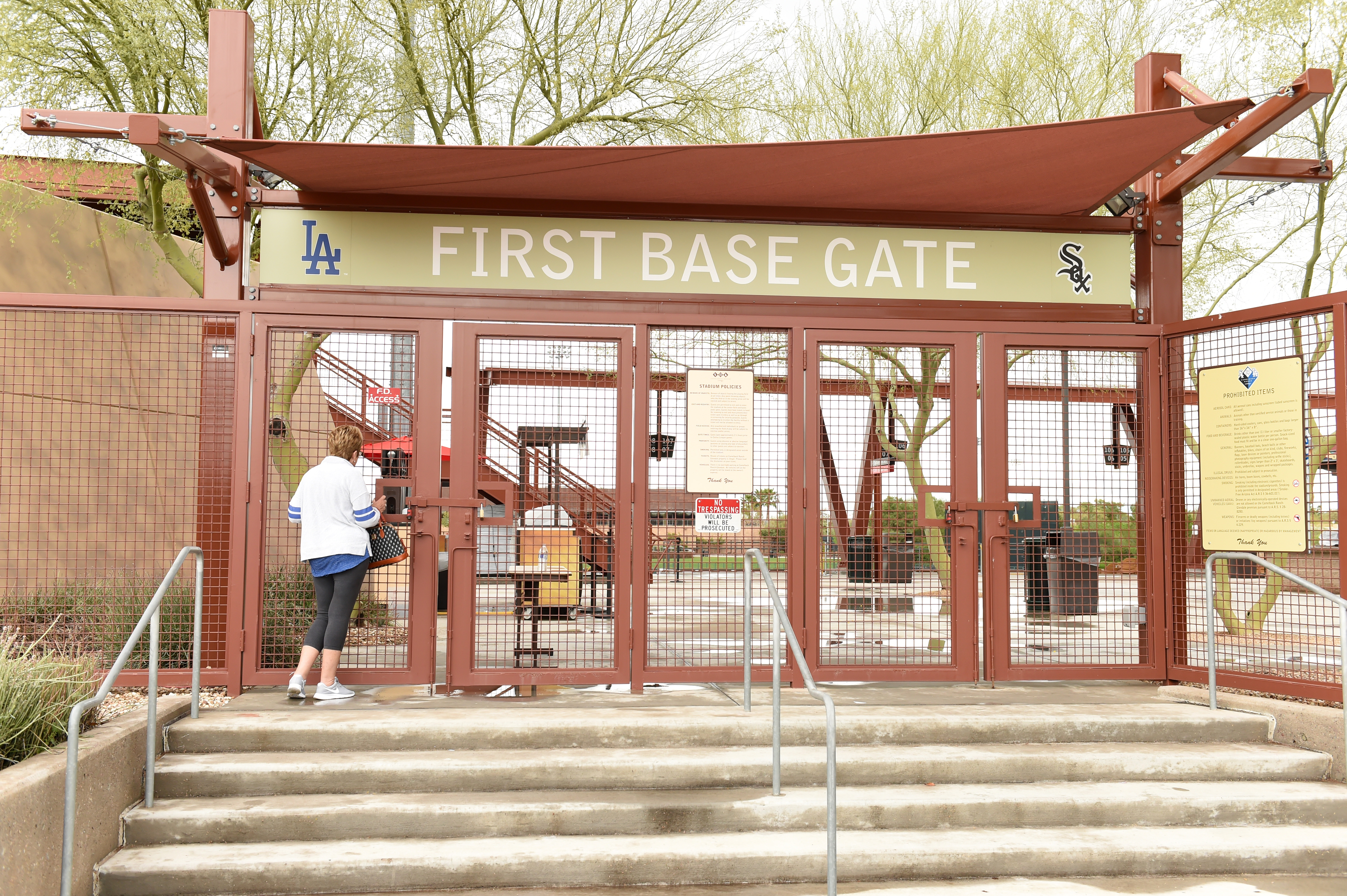 Un fanático de Los Dodgers de Los Ángeles mira a través de la puerta de la primera base en Camelback Ranch después de que las Grandes Ligas (MLB) suspendiera el Entrenamiento de Primavera el 12 de marzo de 2020 en Glendale, Arizona. La MLB suspendió el entrenamiento de primavera debido a la continua amenaza del brote de coronavirus (COVID-19). (Foto de Norm Hall / Getty Images)