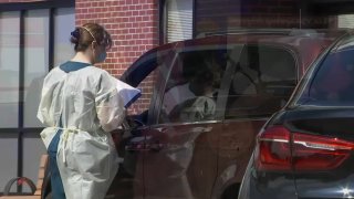 A healthcare worker tests a patient in a car.