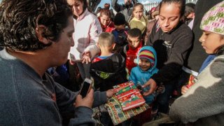 Migrantes reciben regalos navideños.