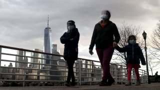 Sunset on Lower Manhattan in New York City as people walk by with masses and face shields