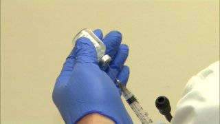 a gloved hand holds a dose of a flu vaccine