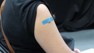 A blue bandaid on an arm