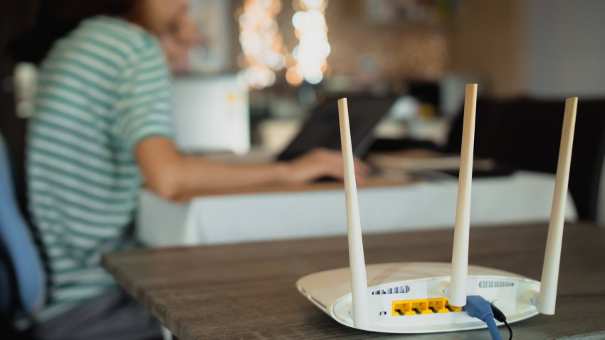 A woman is working at home using a modem router, connecting the Internet to her laptop.