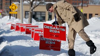 Un voluntario sumerge carteles de campaña para el candidato presidencial republicano, el gobernador de Florida, Ron DeSantis, en la nieve profunda un día antes de las asambleas electorales de Iowa el 14 de enero de 2024, Iowa