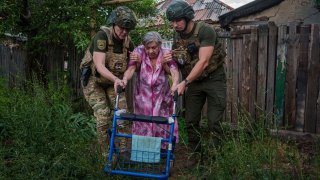 Agentes de la unidad de policía Ángeles Blancos ayudan a una mujer mayor a llegar a una camioneta durante una evacuación, en Toretsk, en la región ucraniana de Donetsk, el 28 de junio de 2024.