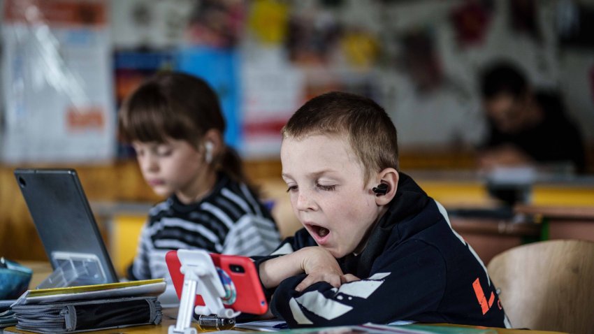 Niño usando un celular en clase