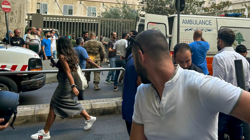 People react near an ambulance as the wounded are brought to a hospital in Beirut.