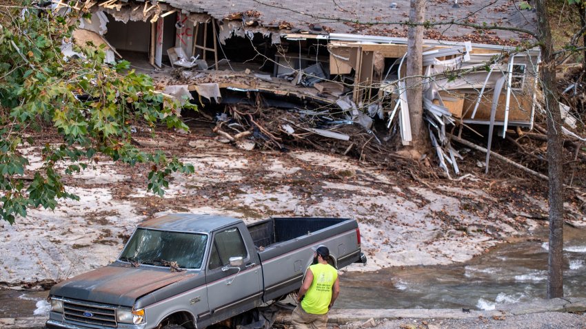 BLACK MOUNTAIN, NORTH CAROLINA – OCTOBER 6: A man inspects a truck for salvage  teetering on a wall next to the Broad River where a house has washed down behind it after flooding from Hurricane Helene on October 6, 2024 in Black Mountain, North Carolina. The truck and house are casualties of flash flooding. The area has been cut off from power with limited road access since Sept 27th when Category 4 Hurricane Helene came from the Gulf of Mexico striking the panhandle of Florida quickly raking north through Georgia, South Carolina, North Carolina and Tennessee dumping as much as 25 inches of rain in some areas. Massive flooding in the mountainous regions of Western North Carolina and Eastern Tennessee cut off power and cell service and made roads impassable. (Photo by Steve Exum/Getty Images)