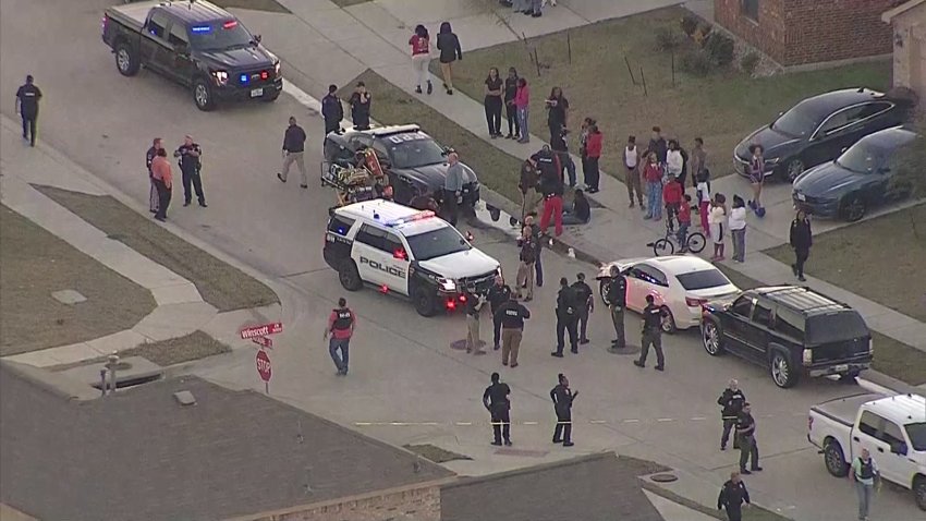 A large number of people gather around law enforcement vehicles in the Windmill Farms neighborhood in Forney, Thursday, Dec. 19, 2024.