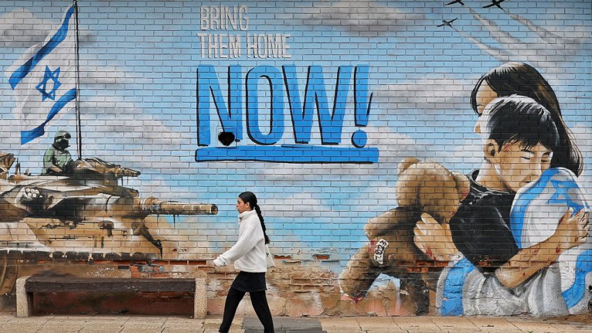 A pedestrian walks past a wall graffiti in the Israeli town of Kfar Saba on January 24, 2025, calling for the release of Israeli hostages held in Gaza since the October 7, 2023 attacks, after a ceasefire deal in the war between Israel and Hamas in the Palestinian territory. The families of Israeli hostages held in Gaza are trapped in limbo, a day before the second prisoner exchange of the Israel-Hamas ceasefire, with many having relatives both on the list to be freed and those who aren’t. (Photo by Jack GUEZ / AFP) (Photo by JACK GUEZ/AFP via Getty Images)