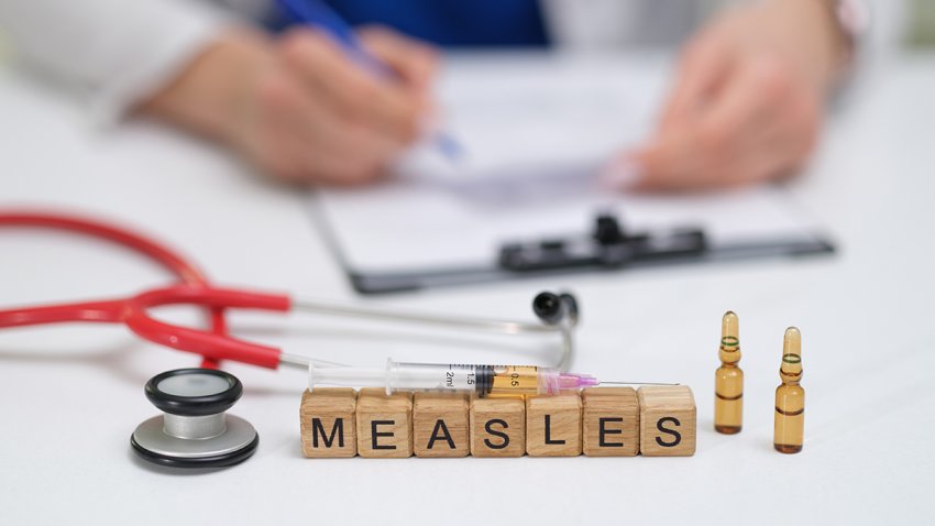 A doctor carefully documents the measles vaccination process, noting the syringes and vials used throughout