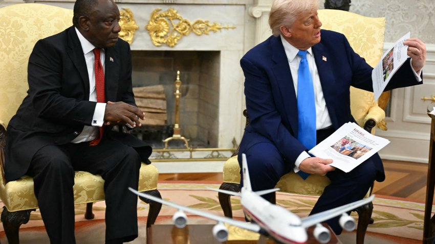 US President Donald Trump shows pictures and articles as he meets with South African President Cyril Ramaphosa in the Oval Office of the White House in Washington, DC, on May 21, 2025. South African President Cyril Ramaphosa meets Donald Trump on Wednesday amid tensions over Washington’s resettlement of white Afrikaners that the US president claims are the victims of “genocide.” (Photo by Jim WATSON / AFP) (Photo by JIM WATSON/AFP via Getty Images)