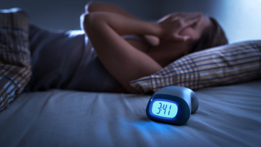 Sleepless woman suffering from insomnia, sleep apnea or stress. Tired and exhausted lady. Headache or migraine. Awake in the middle of the night. Frustrated person with problem. Alarm clock with time.