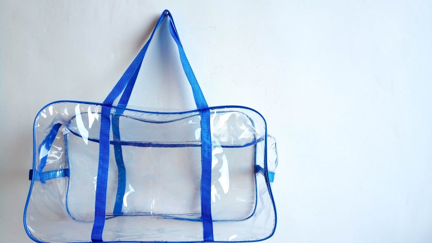 Plastic bag with blue handles hanging on a nail, on a white background.
